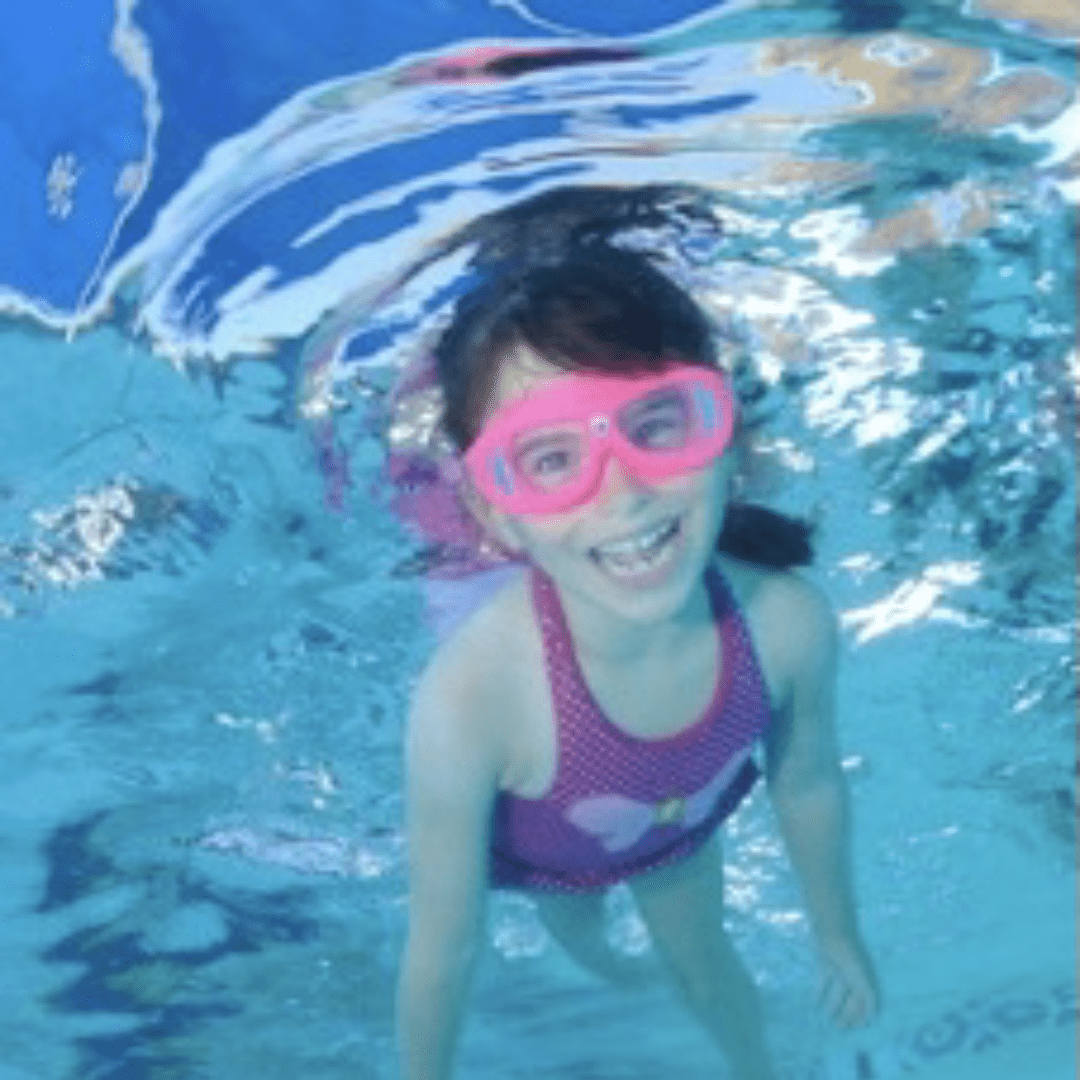 Little girl wearing pink swimsuit smiling underwater the pool