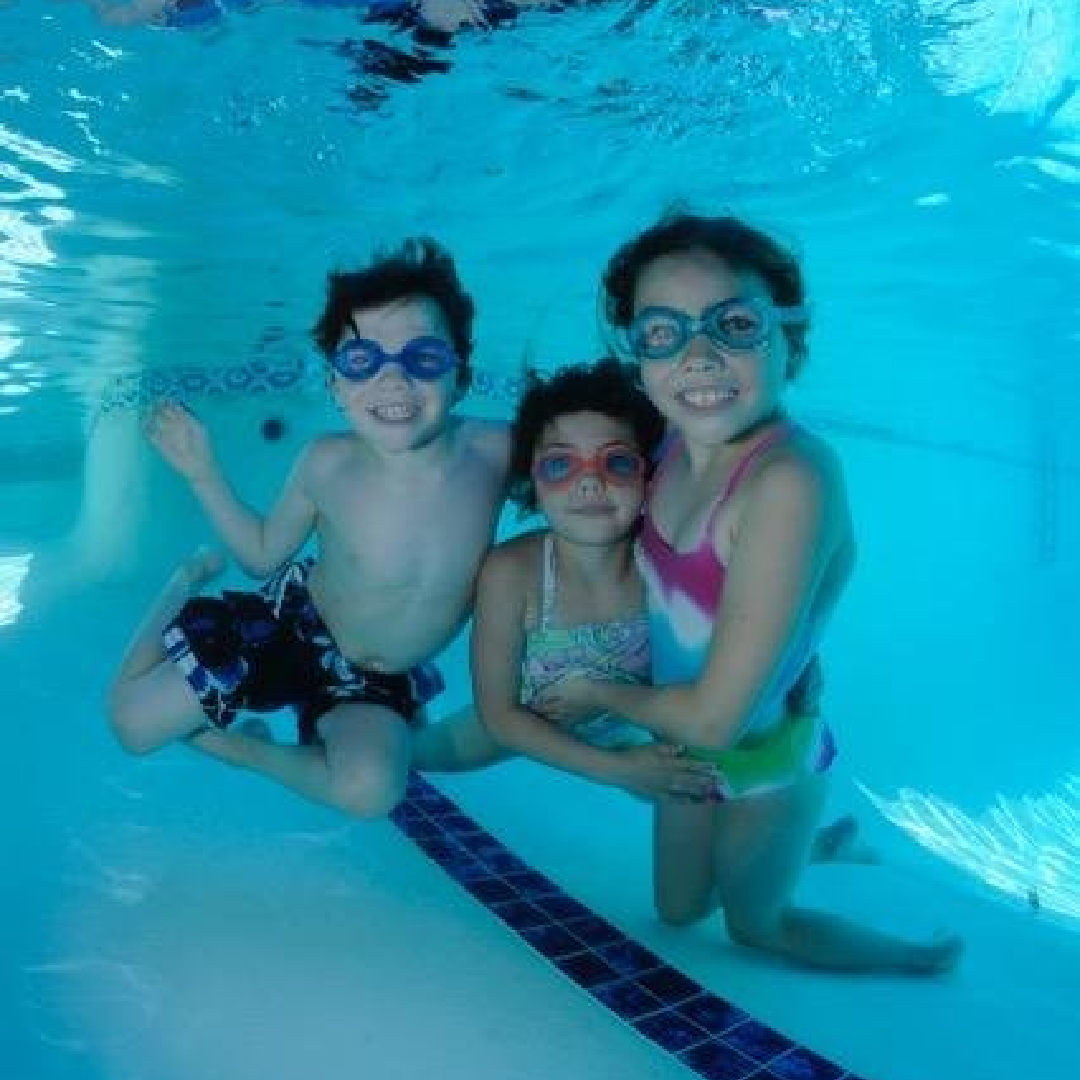 Three kids smiling underwater the swimming pool